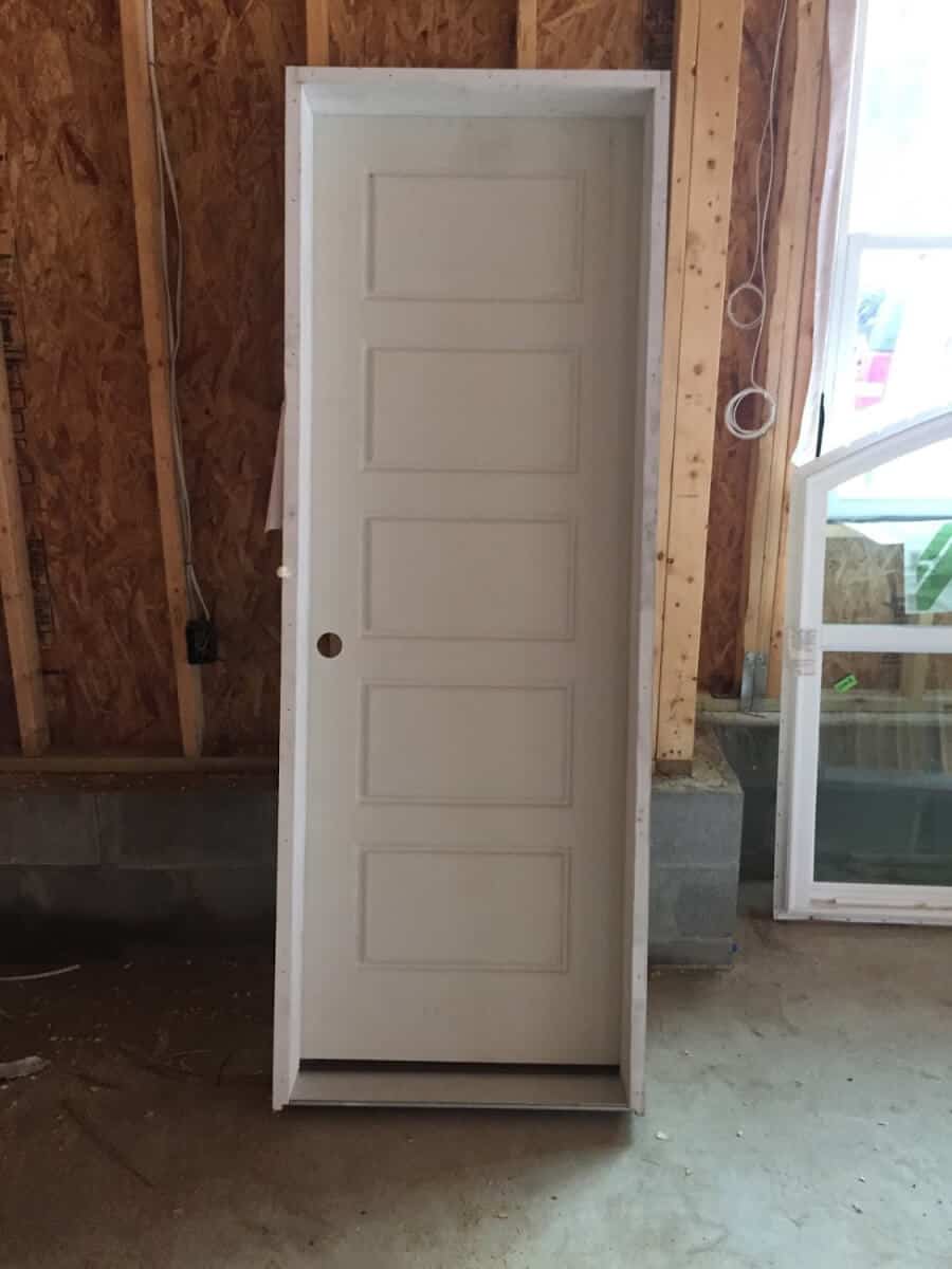 Interior farmhouse door with five panels on it. Sitting inside a garage.