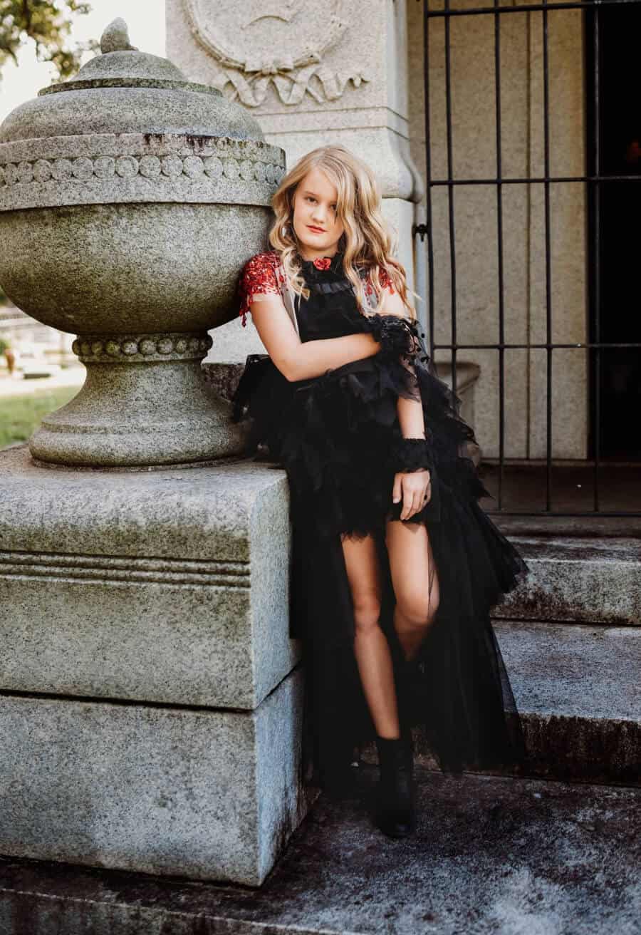 Girl in Halloween costume in old cemetery.