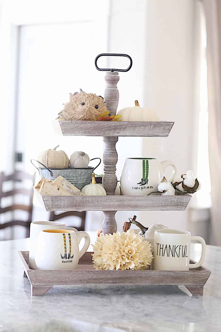 A 3 tier tray with Rae Dunn Mugs and cotton and fall decor