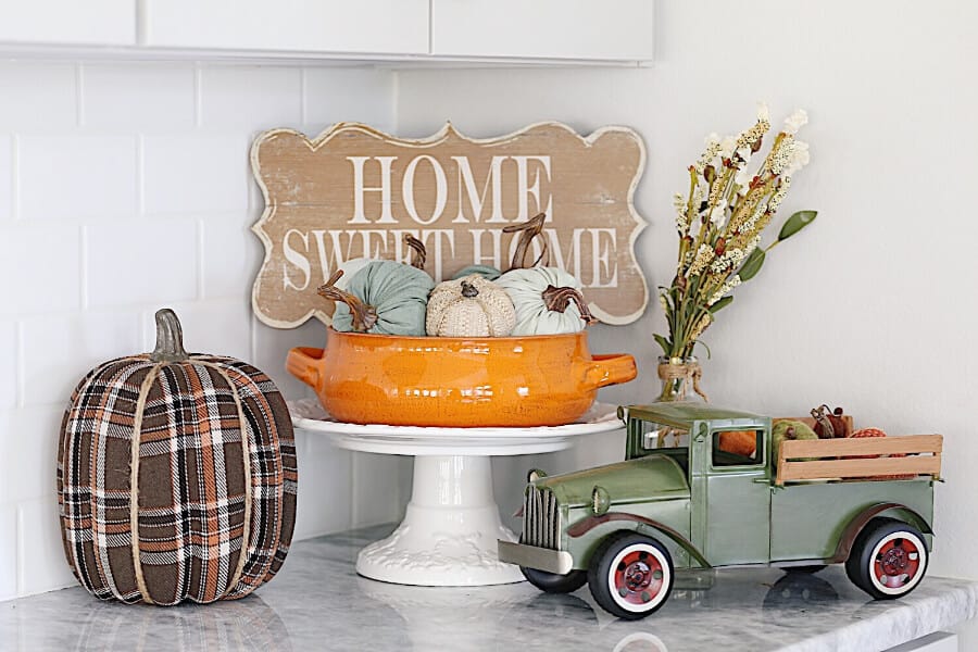 Home Sweet Home sign on a kitchen counter with a vintage truck full of Pumpkins.