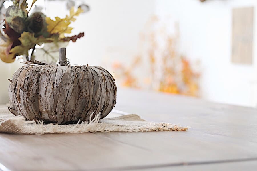 A wooden farmhouse table with wooden pumpkins