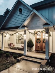 Cozy holiday decorated house with wreaths, string lights, and inviting front porch for festive cheer.
