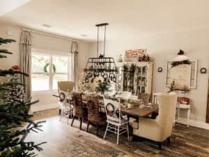 Cozy Christmas dining room with a decorated table, holiday wreaths, and festive decor in a warmly lit space.