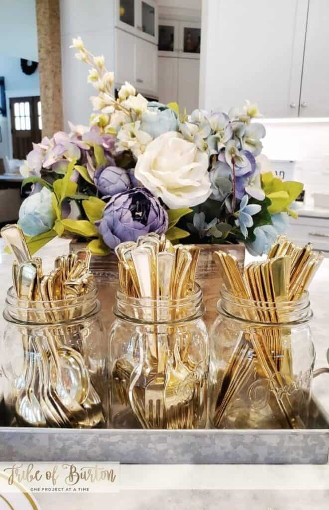 Gold silverware with a spring flower arrangement behind it.