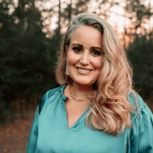 Woman smiling outdoors at sunset, vibrant natural setting, embracing community and nature, representing Tribe of Burton's outdoor lifestyle, authenticity, and connection.