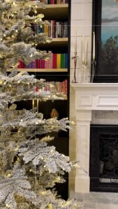 Frosted Christmas tree with warm lights in a cozy modern living room.