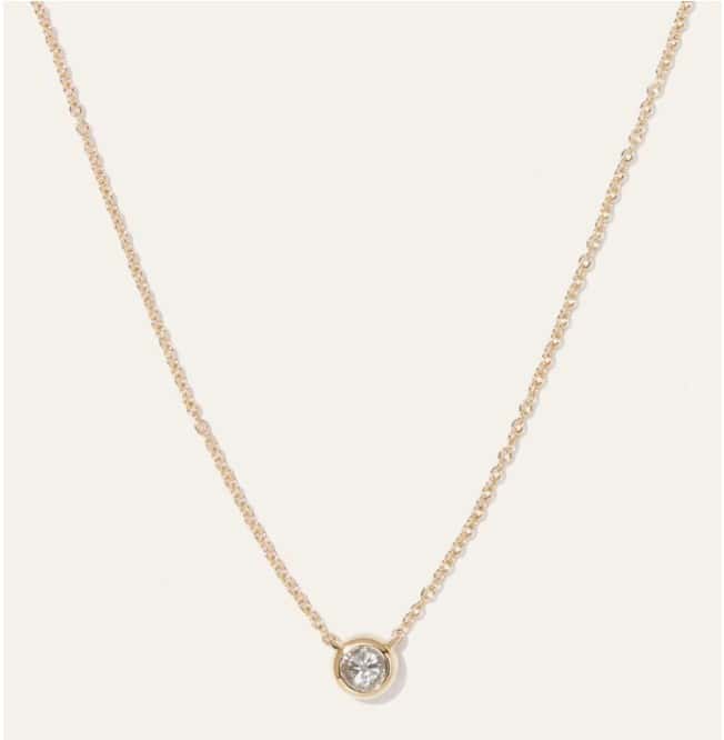 Delicate gold necklace with round diamond pendant, perfect for elegant jewelry styling.