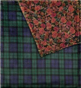 Green and blue tartan fabric with floral patterned cloth layered on top.